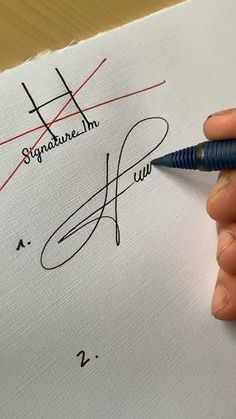 a person writing on a piece of paper with a pen in their left hand and signature written on it