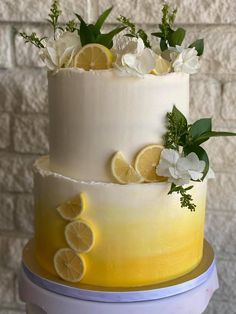 a three tiered cake with lemons and flowers on top