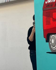 a man taking a picture of a painting on the side of a building with his cell phone