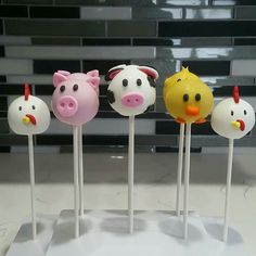 five cake pops with farm animals on them in the shape of pigs, chickens and cows