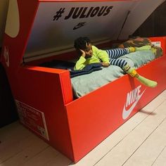 a young boy sitting on top of a red nike bed