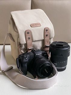 two cameras sitting next to each other on a table with a camera strap around it