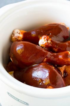 a white bowl filled with hot dogs covered in sauce