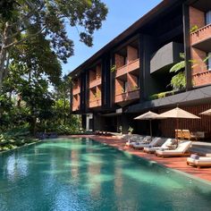 an outdoor swimming pool with chaise lounges and umbrellas next to the building