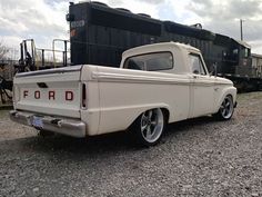 an old pickup truck parked in front of a train