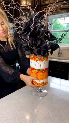 a woman is decorating a halloween cake with candy and sprinkles on it