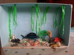 an open cardboard box filled with sea animals and plants on top of a polka dot table cloth