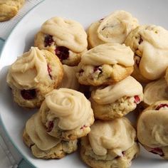 a white plate topped with cookies covered in frosting and cranberry toppings