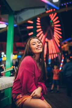 a woman sitting on a bench in front of a ferris wheel