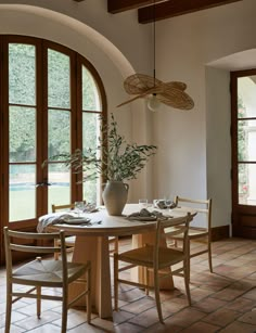 a dining room table and chairs in front of large windows with arched wooden doors leading to the outside