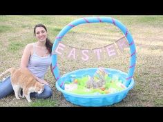 a woman sitting in the grass with her cat next to an easter basket and sign