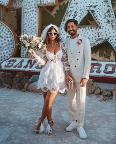 a bride and groom pose for a photo in front of the neon sign at las vegas