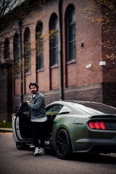 a man standing next to a green sports car