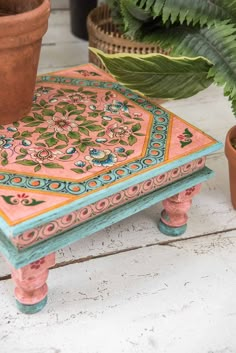 a pink and blue table sitting next to a potted plant