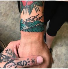 a person with a tattoo on their arm holding onto another persons hand and looking at the camera