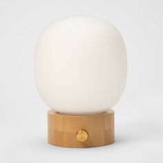 a white ball sitting on top of a wooden stand next to a light brown base