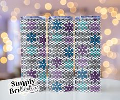 two purple and blue can coolers sitting on top of a white table with lights in the background