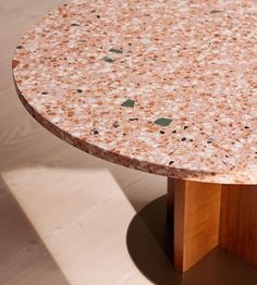 a marble table with wooden legs on a hard wood flooring area in a room