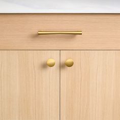 a wooden cabinet with two brass knobs on the front and one has a door handle