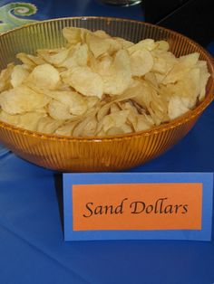 a bowl filled with chips sitting on top of a table next to a sign that says sand dollar's