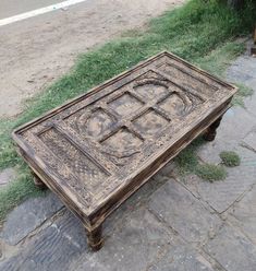 an old wooden table sitting on the ground in front of some grass and dirt area