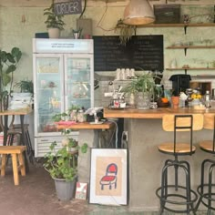 the interior of a small cafe with plants and potted plants on the bar counter