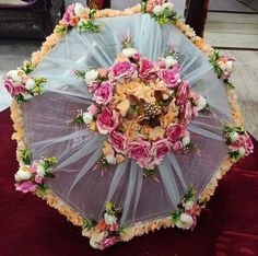 an umbrella decorated with flowers and tulle is sitting on a red velvet flooring