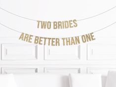 two brides are better than one banner in gold foil on a white bed with pillows