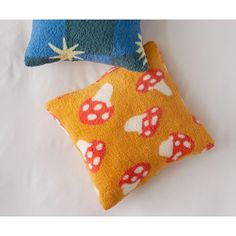 two decorative pillows on top of each other, one with mushroom print and the other in blue