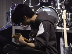 a young man sitting on top of a stage holding a guitar