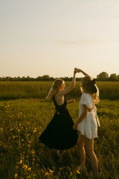 two young women are dancing in a field