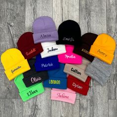 many different colored beanies on a wooden floor with the word name written in them