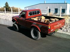 a red pick up truck with logs in the bed