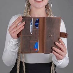 a woman with braids is holding an open wallet and credit card holder in her hands