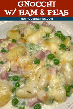 a white plate topped with pasta covered in ham and peas on top of a wooden table