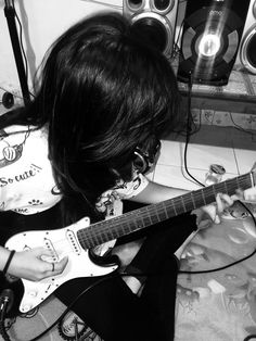 a girl playing an electric guitar in front of some speakers