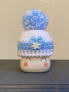 a blue and white crocheted hat sitting on top of a wooden table next to a wall