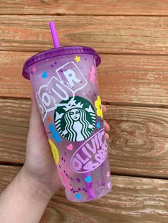 someone is holding up a purple starbucks cup