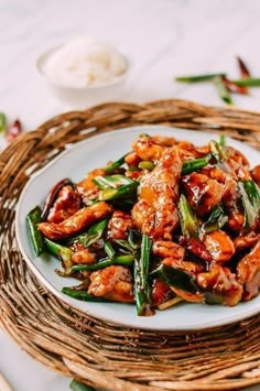 a white plate topped with chicken and green beans on top of a wicker place mat