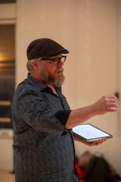 a man with glasses and a hat holding a tablet