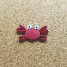 a red crab with googly eyes sitting on the ground