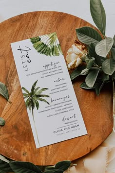 a wooden plate with a menu on top of it next to greenery and flowers