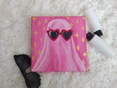 a pink painting with heart shaped glasses on it next to sunglasses and a pair of black eyeglasses