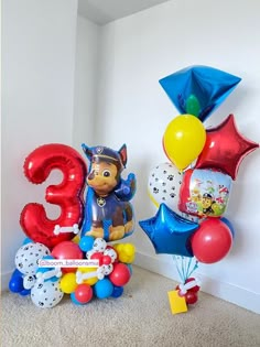 some balloons are sitting on the floor next to a number 3 and balloon bouquets