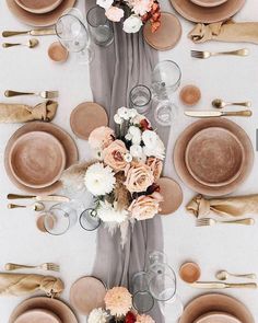 the table is set with plates, silverware, and flowers on top of it