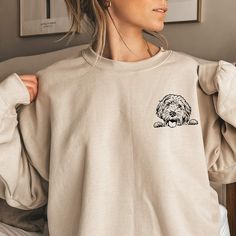 a woman wearing a sweatshirt with a dog embroidered on it