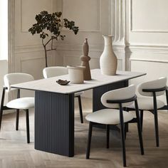 a dining table with chairs and vases on it