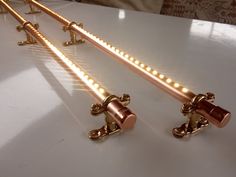 three gold colored candles are sitting on a white table with some lights in the middle