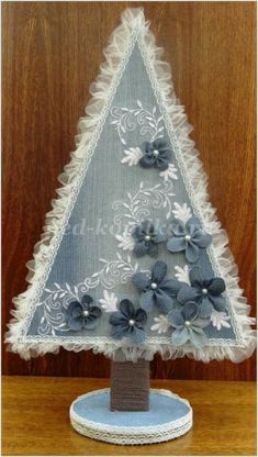 a blue and white christmas tree made out of doily on a wooden table top