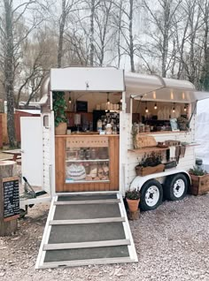 a food truck parked in the woods with its door open and shelves full of items